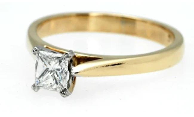 An exquisitely designed princess-cut diamond ring, highlighting the sharp, symmetrical facets of the central diamond. 