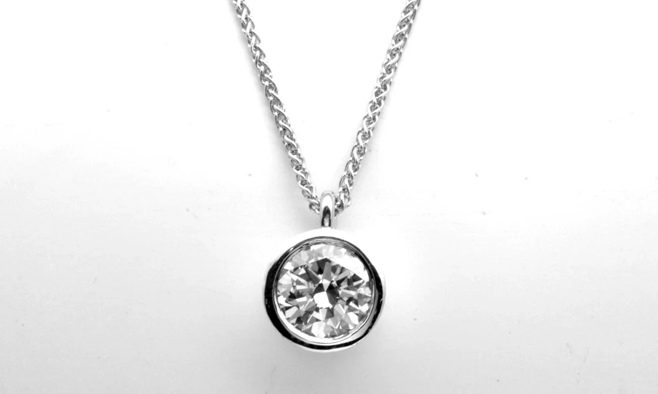 A radiant, perfectly round-cut diamond pendant that sparkles brilliantly against a simple white background, showcasing the exceptional craftsmanship and timeless elegance. 