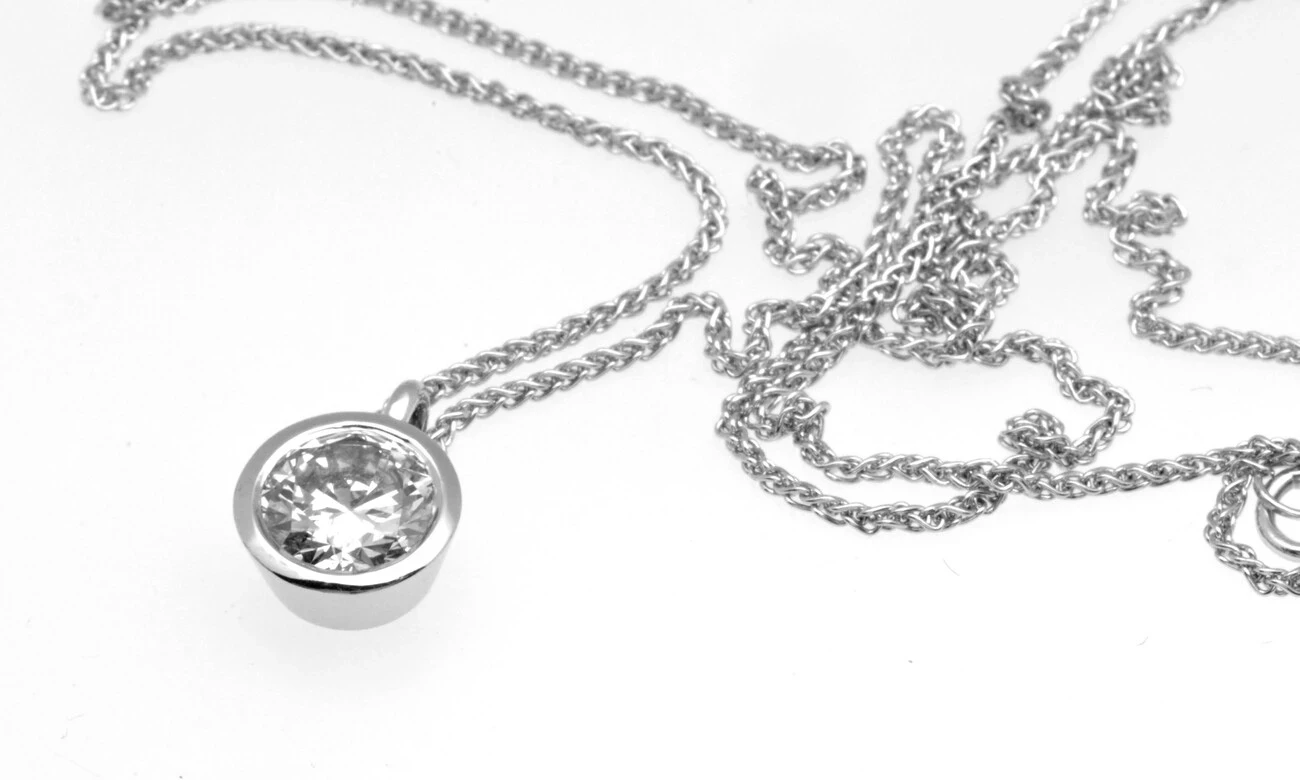  A stunning 1.0-carat diamond pendant elegantly suspended from a delicate platinum chain, reflecting light with unmatched brilliance and clarity. 