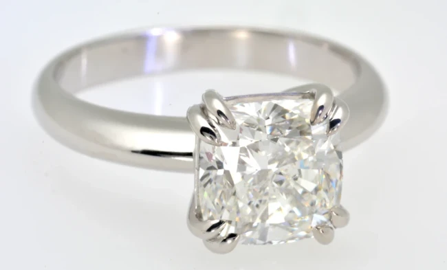 A stunning 3.05-carat cushion-cut diamond solitaire ring sitting elegantly on a black velvet background. 