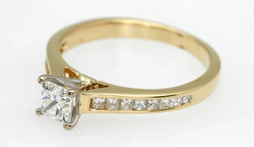 A polished gold ring with a single large diamond at its centre, displayed against a clean white background.