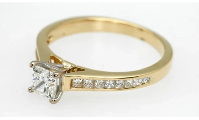 A polished gold ring with a single large diamond at its centre, displayed against a clean white background. 
