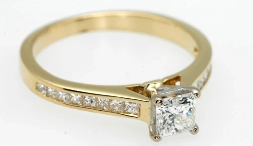 A dapper gentleman named Adrian is elegantly dressed in a tailored suit and tie, standing confidently in a modern jeweller's showroom.