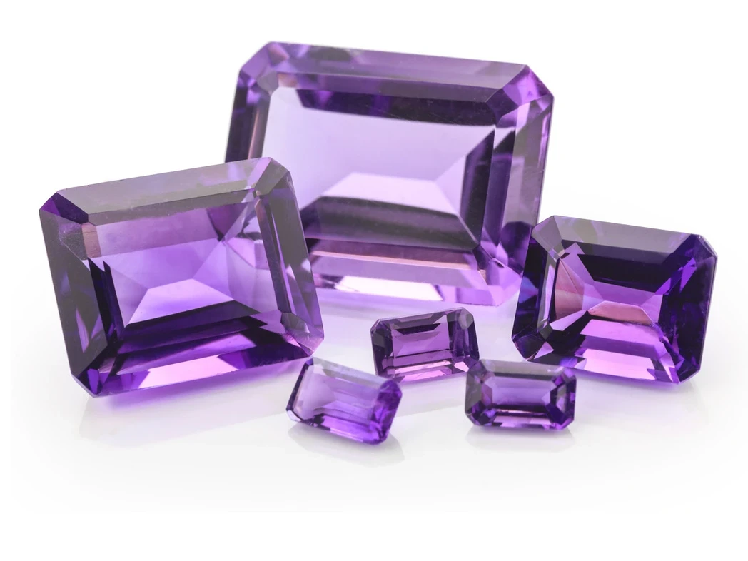 A stunning rectangular-cut amethyst gemstone set against a neutral background, showcasing its deep purple hue and precise faceting.