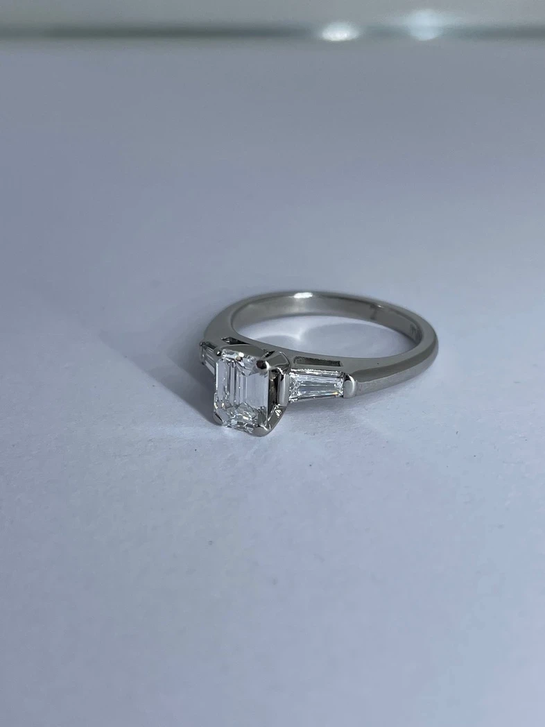 An elegant emerald-cut diamond engagement ring set in a timeless platinum band. 