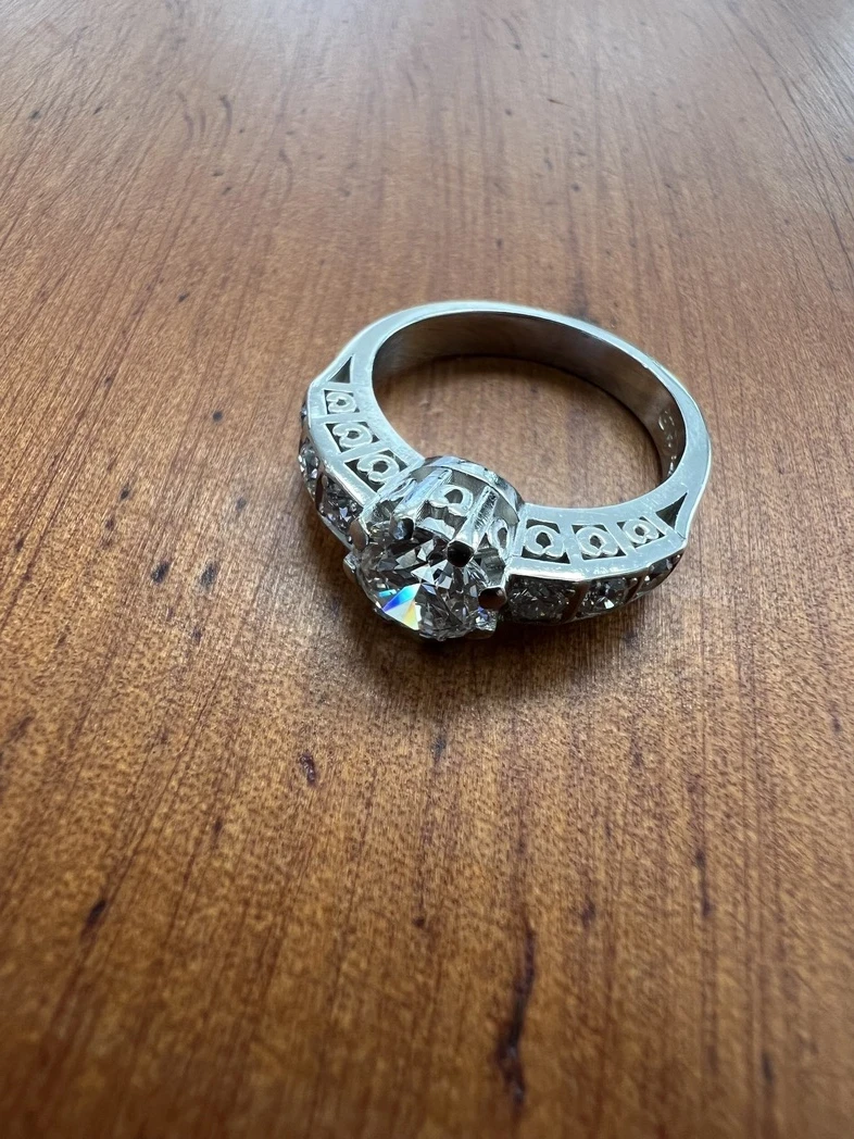 A vintage estate diamond ring featuring an exquisite large central diamond, surrounded by a halo of smaller, brilliant-cut diamonds, set in a timeless platinum band. 