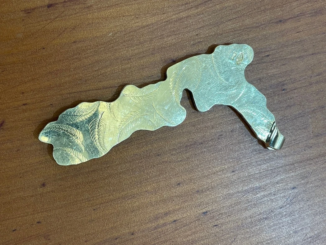 A beautifully handcrafted pendant shaped like the map of New Zealand with intricate details and a polished finish, highlighting the artisanal craftsmanship unique to Aurum Fine Jewellery. 